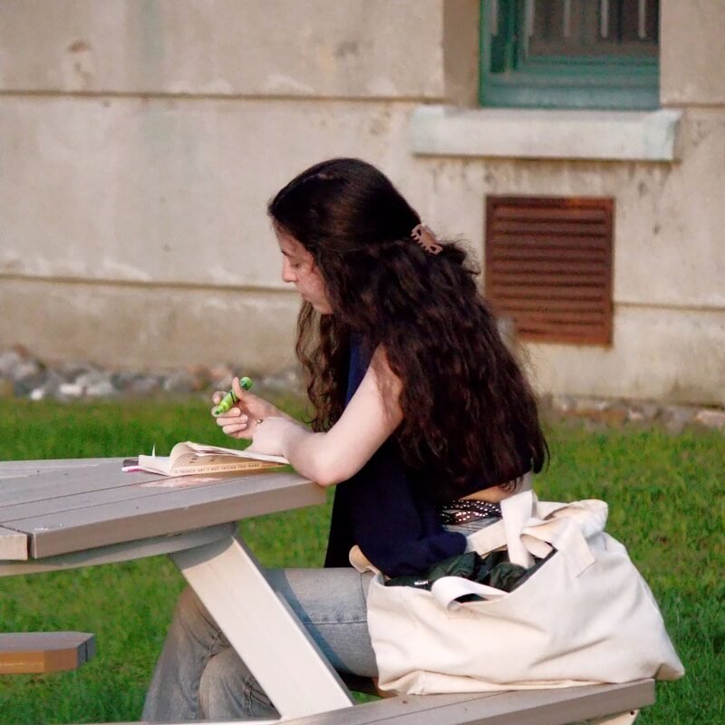 a woman sitting at a picnic table eating a sandwich